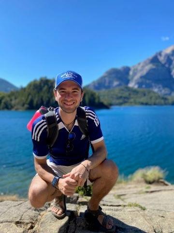 Joseph Richard outside on a rock near a body of water on a clear day